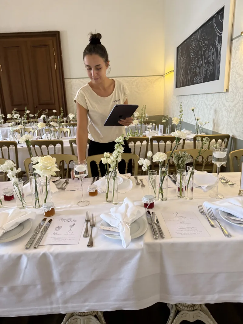 Planerin prüft Details an festlich gedeckter Tafel