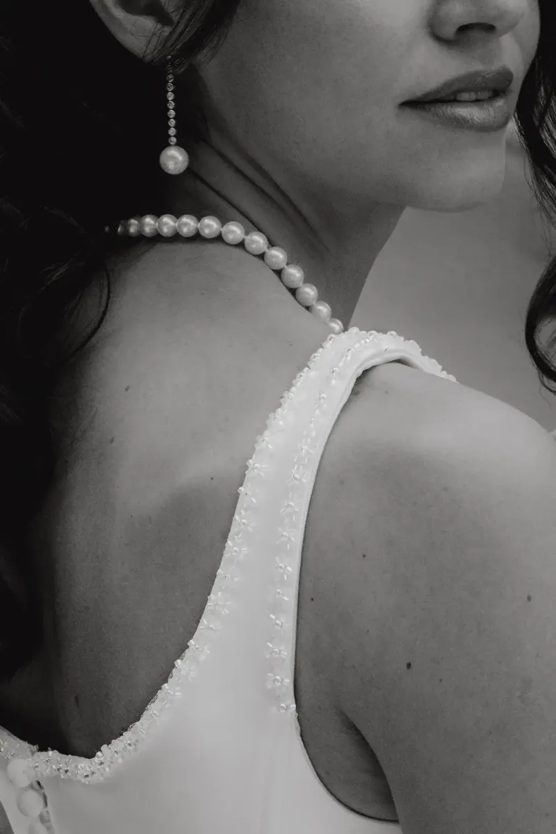 Detail der Braut mit Perlenkette und Spitzenkleid von hinten