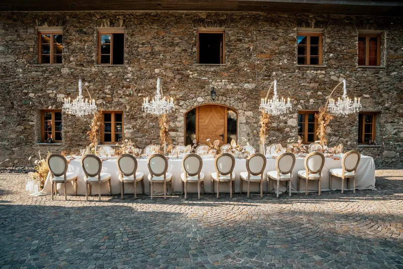 Lange festliche Tafel vor historischem Steingebäude im Freien