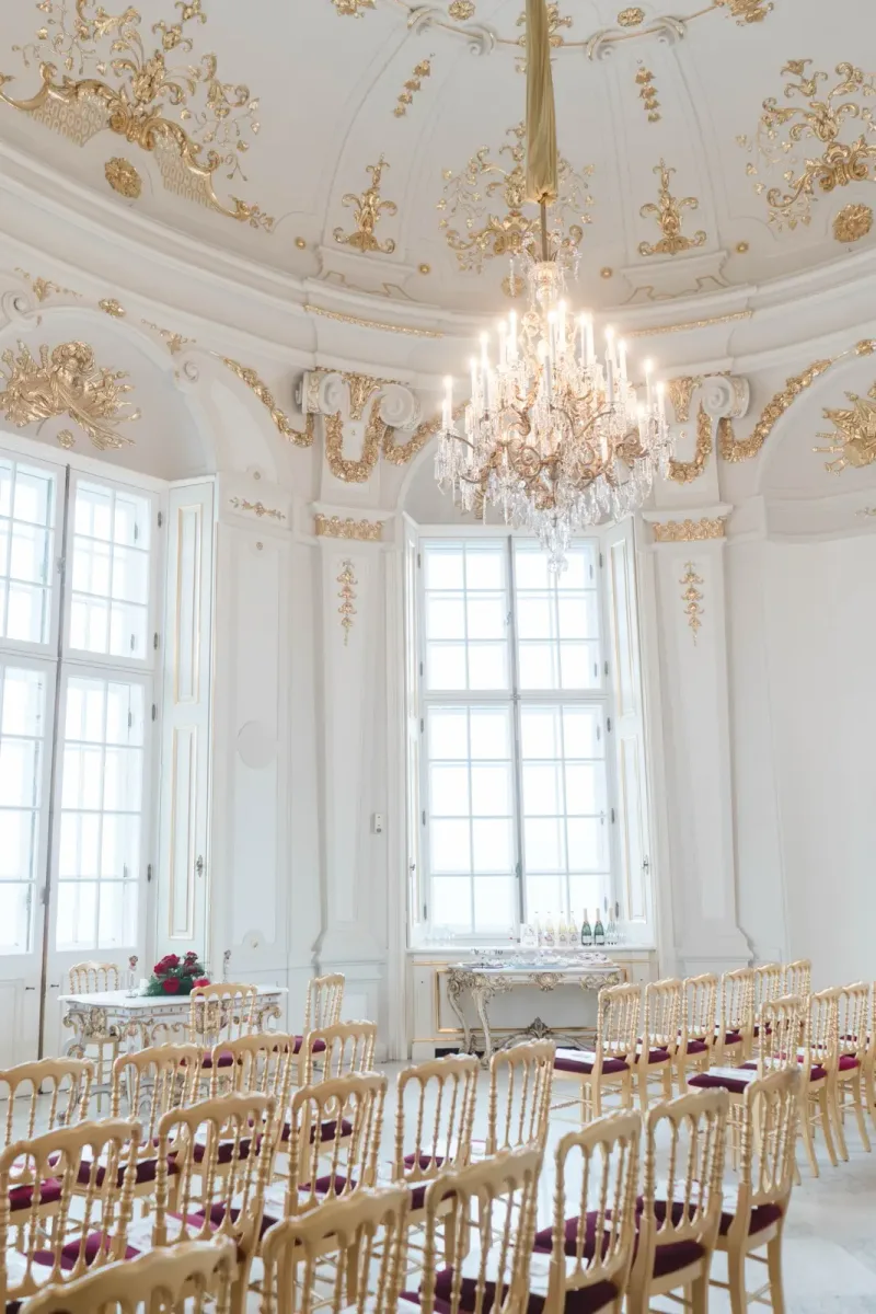 Historischer Festsaal mit Reihen goldener Stühle und Lichtern